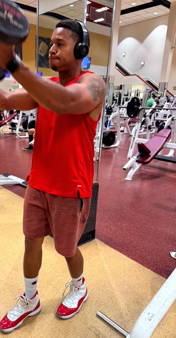 Dustin King mid-set, raising a dumbbell in the gym.